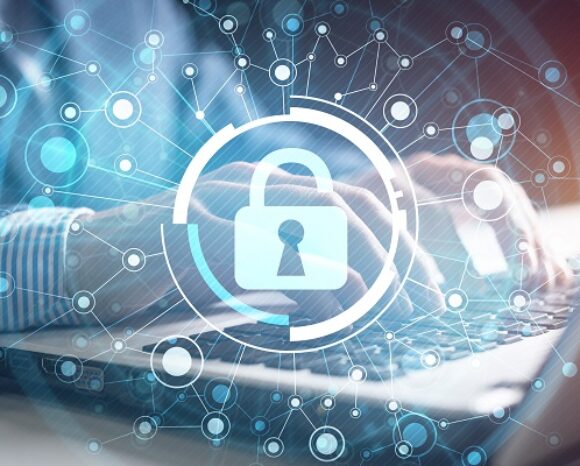 Eine Person tippt auf einem Laptop, überlagert mit der digitalen Grafik eines Vorhängeschlosses, umgeben von miteinander verbundenen Knoten und Linien, als Symbol für Cybersicherheit und Datenschutz – ein entscheidender Schwerpunkt angesichts zunehmender globaler Spannungen wie dem Ukrainekrieg.