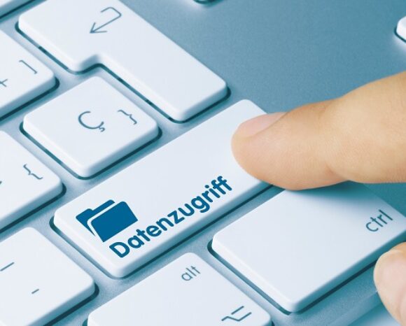 Der Finger einer Person drückt auf einer Nahaufnahme einer Tastatur die Taste „Datenzugriff“ und deutet damit auf Zugriff oder Konnektivität hin. Die weißen Tasten mit grauer Schrift stehen auf einem hellen Hintergrund und betonen so Klarheit und Einfachheit.