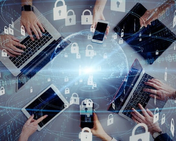 Hände, die verschiedene elektronische Geräte wie Smartphones und Tablets halten, umrahmen einen digitalen Globus. Darüber sind Vorhängeschloss-Symbole und Binärcode zu sehen, die Cybersicherheit, globale Konnektivität und die Abwehr von Cyberangriffen symbolisieren.