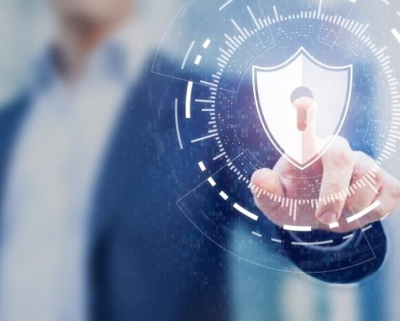 Eine Person im Anzug zeigt auf eine digitale Sicherheitsschnittstelle mit einem Schildsymbol und einem Schlüsselloch. Der unscharfe Hintergrund betont die Passwortsicherheit. Helle, futuristische Grafiken umgeben das Schild und vermitteln ein Gefühl von Schutz.
