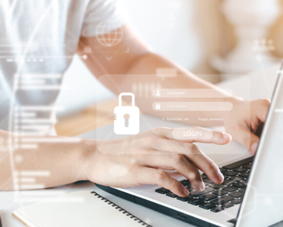 Eine Person tippt auf einem Laptop. Auf einer digitalen Einblendung wird ein Anmeldebildschirm mit Feldern für Benutzername und Passwort sowie einem Vorhängeschlosssymbol und Firewall-Grafiken angezeigt, die robuste Cybersicherheit und Online-Datenschutz symbolisieren.