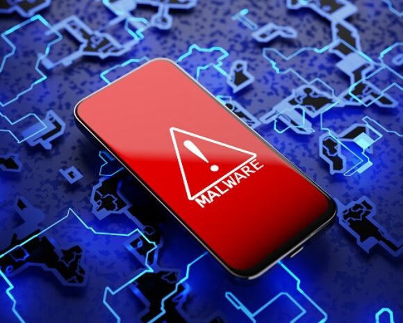 Ein Smartphone mit rotem Display, einem weißen Warndreieck und dem Schriftzug „MALWARE“ liegt auf einer blauen digitalen Platine und symbolisiert eine alarmierende Cybersicherheitsbedrohung. Mit rund 100 Schadsoftware-Varianten pro Minute verdeutlichen solche Angriffe die zunehmende Gefahr für die IT-Sicherheit.