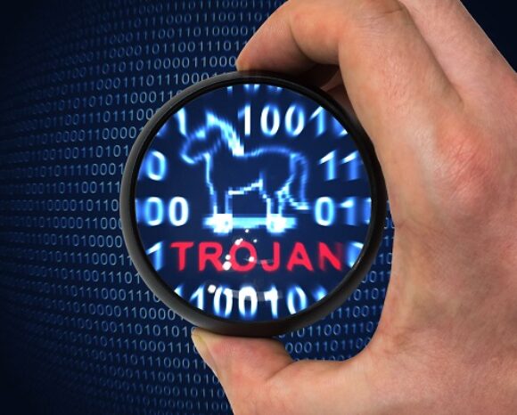 Eine Lupe fokussiert ein digitales Trojanisches Pferd inmitten von Binärcode. „TROJAN“ leuchtet rot und signalisiert eine Bedrohung für die Cybersicherheit. Im Kontext des aktuellen Malware-Rankings: Qbot in Deutschland weiterführend ist Wachsamkeit geboten. Eine Hand hält das Glas vor einem dunklen Hintergrund.
