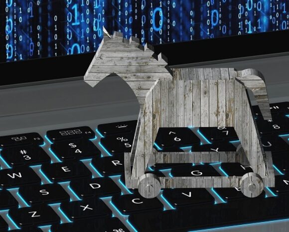 Eine hölzerne Trojanerfigur ruht auf einer Laptop-Tastatur mit leuchtend blauen Tasten und symbolisiert die Tarnung und Bedrohung, ähnlich dem Trojaner in der 3CX Telefon-Software. Im Hintergrund ist ein digitaler Bildschirm mit blauem Binärcode zu sehen.