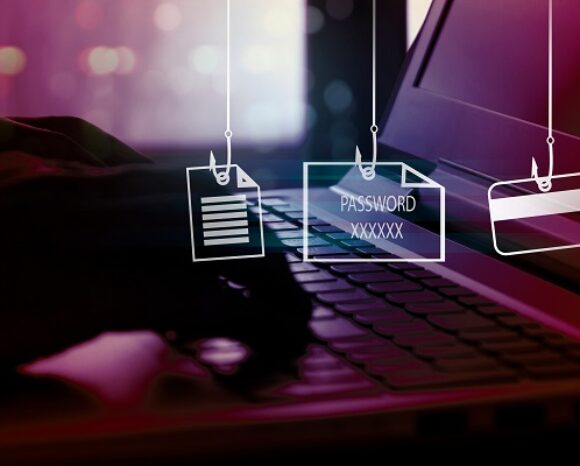 Die Hände einer Person tippen auf einer Laptop-Tastatur. Darüber sind digitale Symbole für Phishing zu sehen – ein Dokument, ein Passwortfeld mit der Aufschrift „Passwort XXXXXX“ und eine Kreditkarte –, die alle mit Angelschnur-Symbolen versehen sind. Dies unterstreicht die Dringlichkeit der Frage, wie sich der Mittelstand vor Cyberangriffen schützen kann.