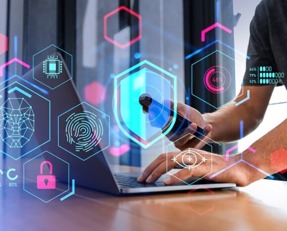 Mann mit Smartphone vor Laptop. Davor Security-Symbole