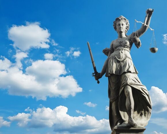 Justizia-Figur vor bewölktem Himmel