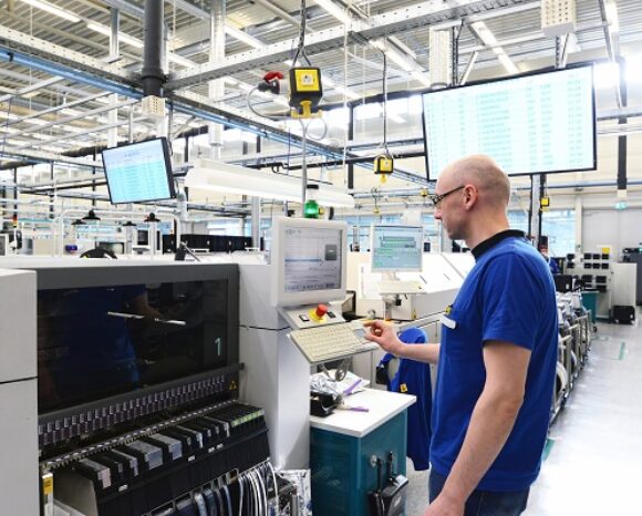 Mann in der Produktionshalle vor einem Monitor