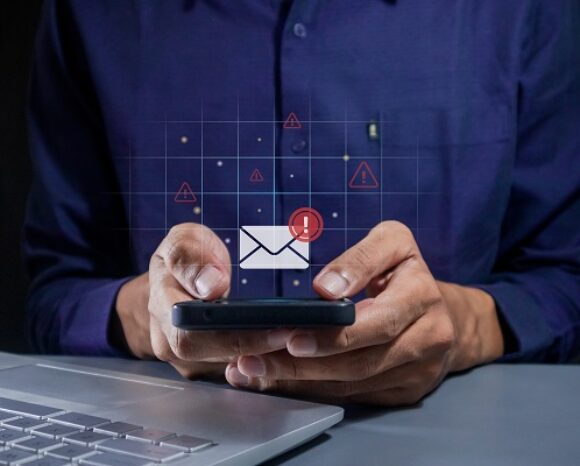Geschäftsmann mit Smartphone und Warnsignal über E-Mail-Symbol