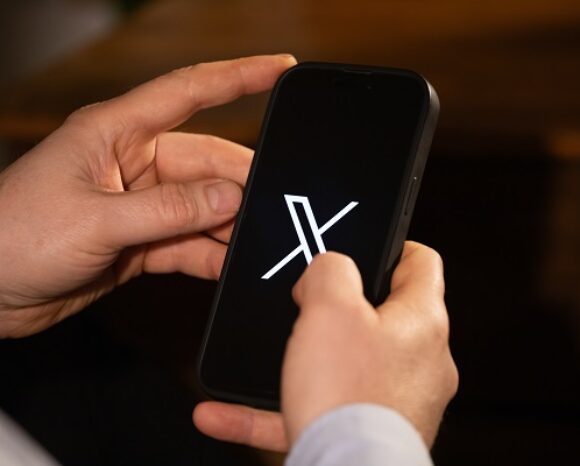 Hände mit Smartphone, die geöffnete X-App zeigt