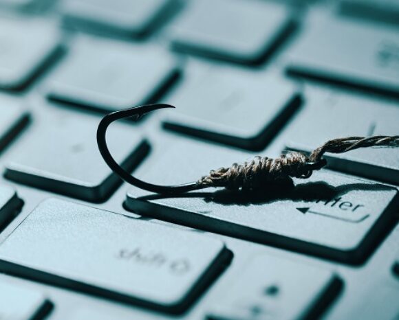 Fischhaken liegt auf Laptop-Tastatur