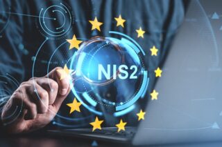 Hand mit Lupe zeigt auf NIS-2-Symbol