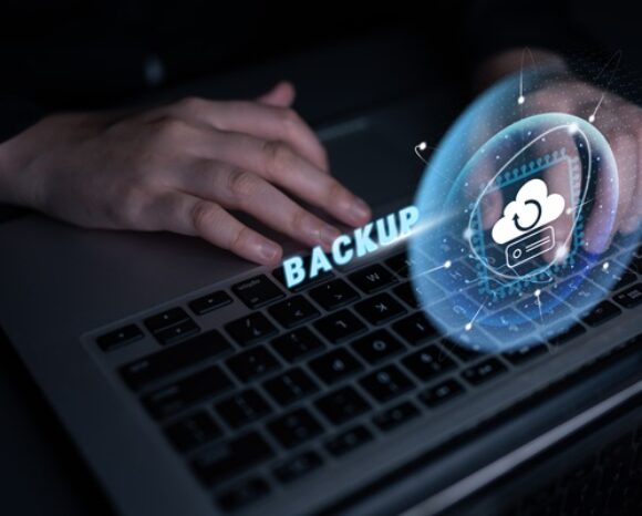 Hand an Tastatur, darüber Symbole für Backup
