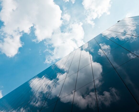 Hochhaus mit Wolken, die darüber ziehen.