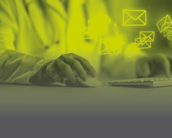 Arzt nutzt Computermaus, fliegende E-Mail-Symbole auf gelb-grauem Hintergrund