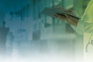 Ärztin mit Tablet vor Krankenhaus-Hintergrund