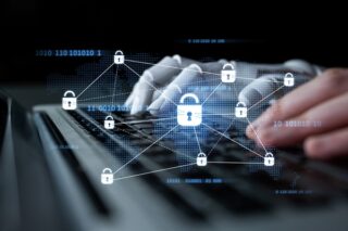 KI- und menschliche Hand tippend auf der Tastatur mit Cybersecurity-Symbol