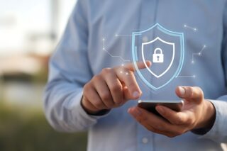 Mann hält Smartphone und tippt auf virtuelles Cybersecurity-Symbol