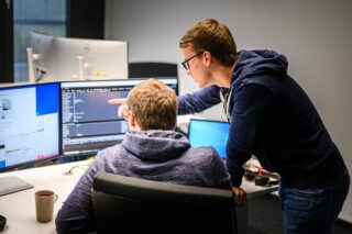 Zwei Männer diskutieren vor Monitoren