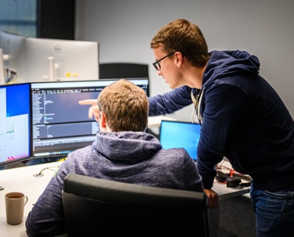Zwei Männer diskutieren vor Monitoren